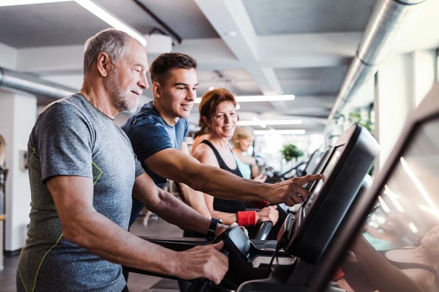 Young man helping the older man with his treadmill