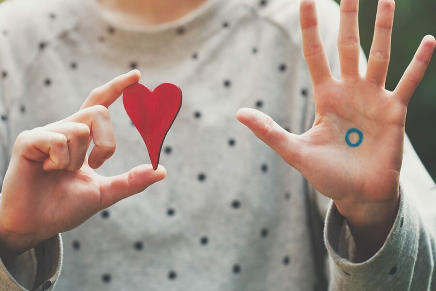 girl holding a heart shape on right hand and showing the blue circle with palm open on the left hand