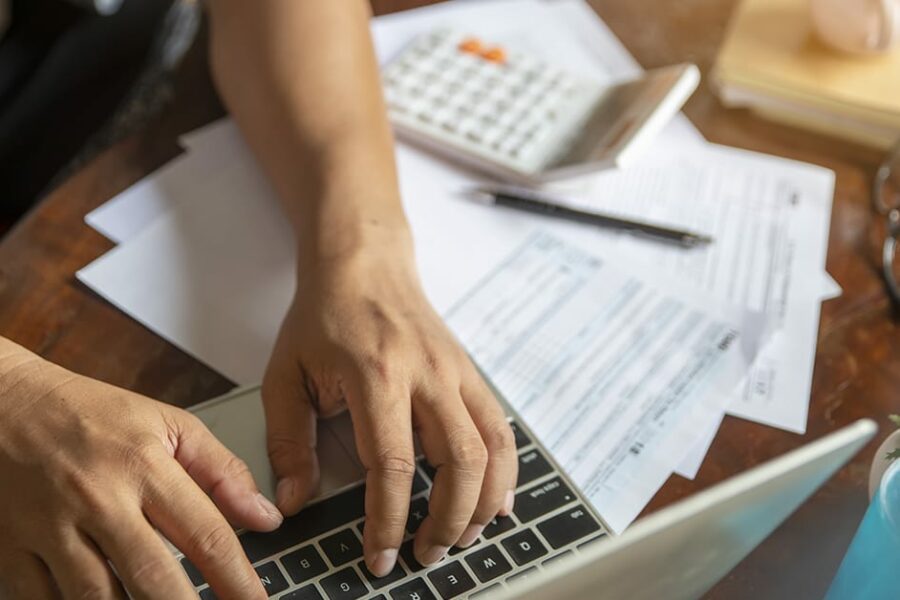 udget and Tax planning concept. Accountant is calculating company's annual tax and typing laptop. Personal income tax form for who have income