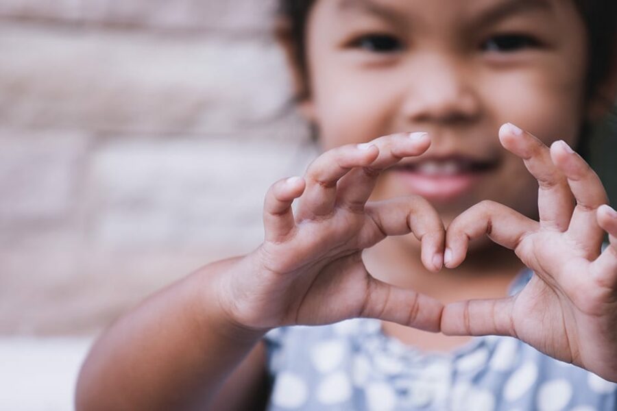 Asian kid doing heart shape with hand