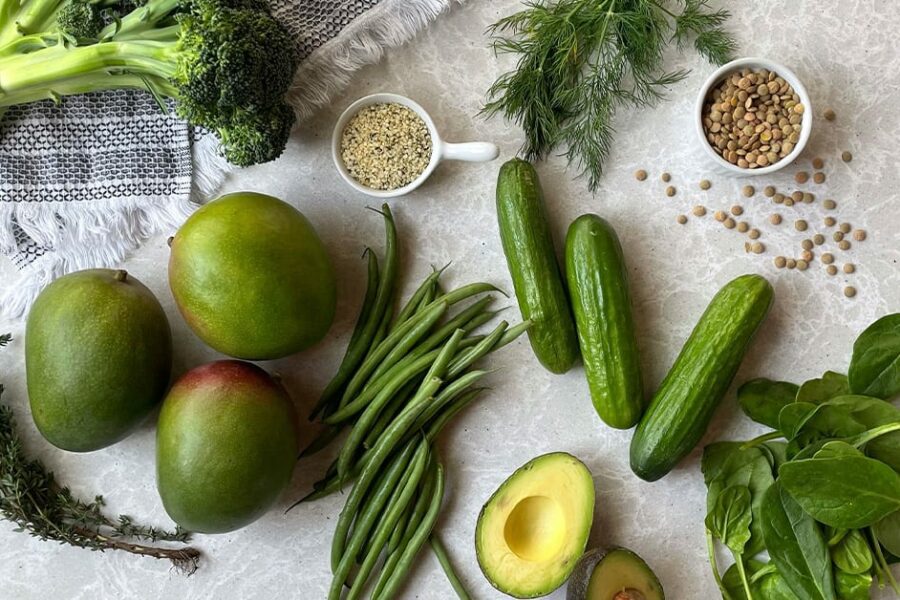 Different green fruits and vegetables on top of the table