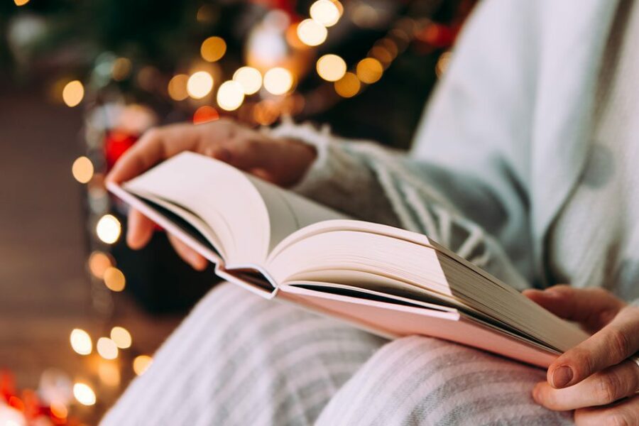 Person in pyjamas reading a book during the Holiday to manage holiday stress