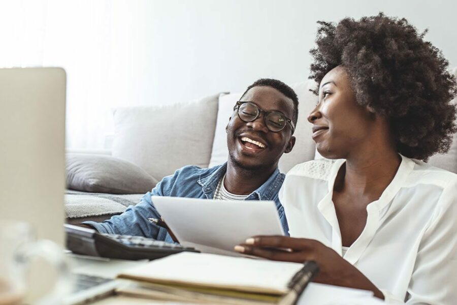 Young married couple doing their paperwork together, paying bills online. Focus on the guy. Loving young couple using laptop and analyzing their finances.