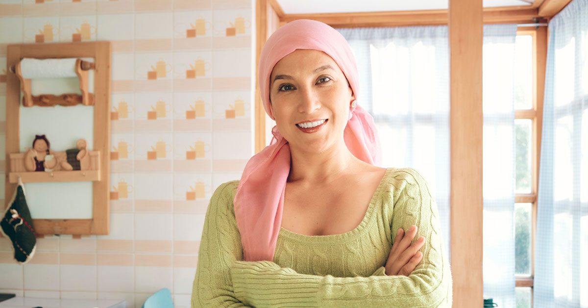 Woman cancer survivor is smiling with her arms crossed and looking at the camera