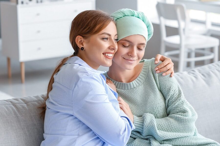 woman hugging a female friend with ovarian cancer in the couch.